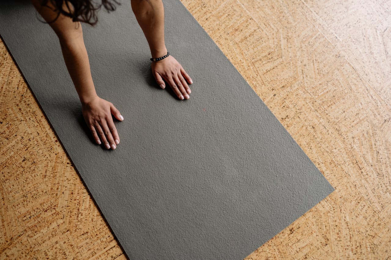 The Art of Drawing Readers In: Your attractive post title goes here Close-up of hands on a grey yoga mat on a wooden floor, from above.